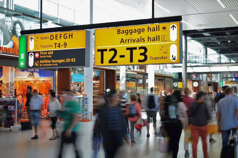 Inside of an Airport with people blurred passing by with airport directional signs
