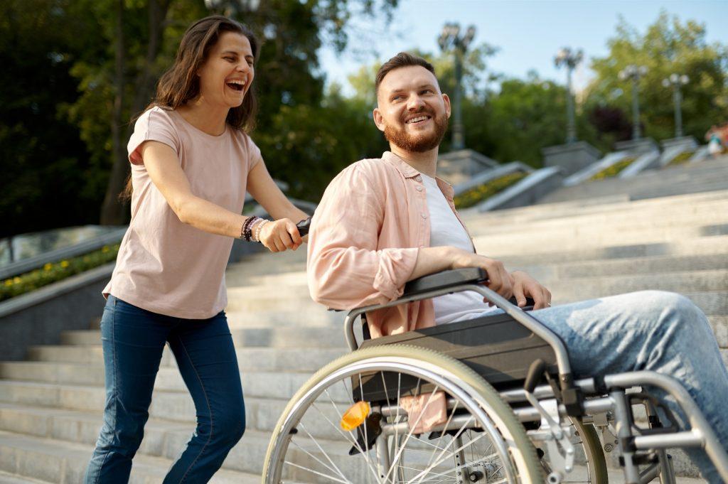 Couple with wheelchair goes up the stairs in park