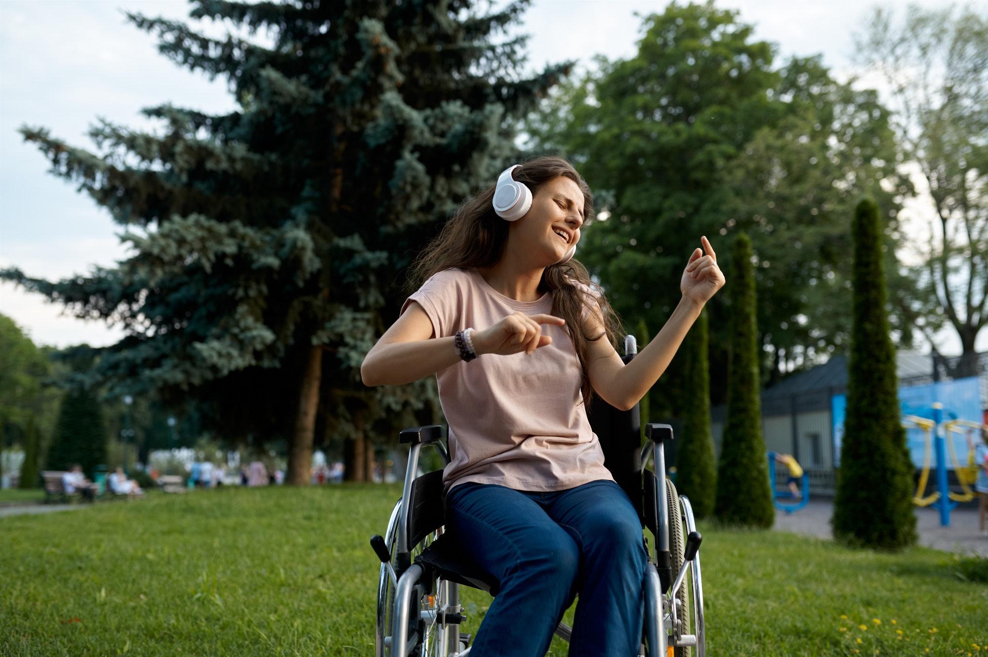Disabled woman in wheelchair listens to music
