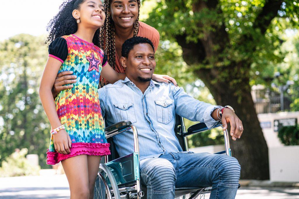 Man in a wheelchair enjoying a walk outdoors with family.