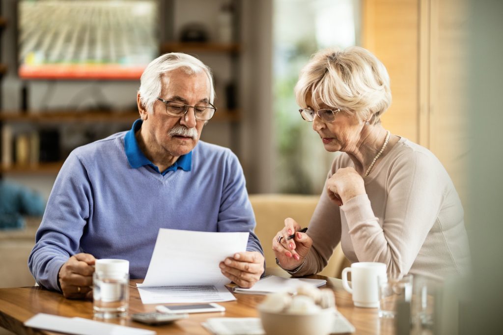Senior couple going through paperwork while analyzing home finances.