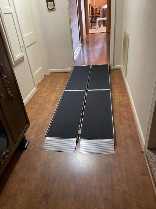 Portable wheelchair ramp connecting wood floor in the hallway to tile