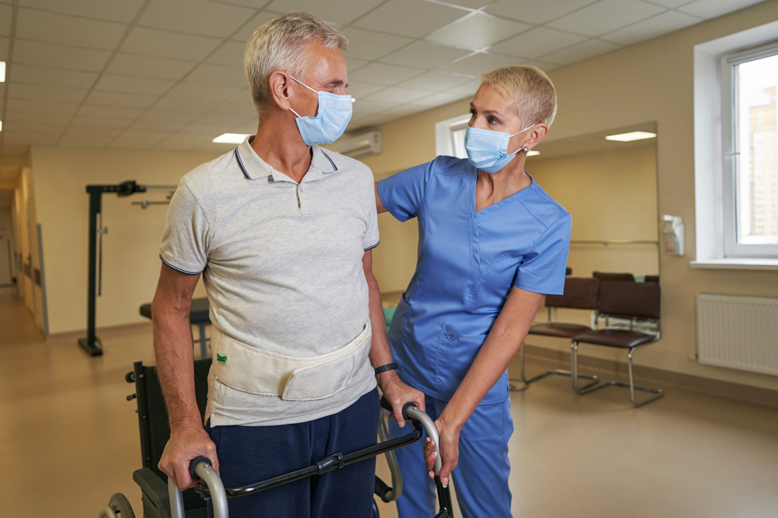 A nurse assists a stroke survivor regain mobility in rehab