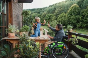 A grandfather in a wheelchair works with his grandson to build a birdhouse.