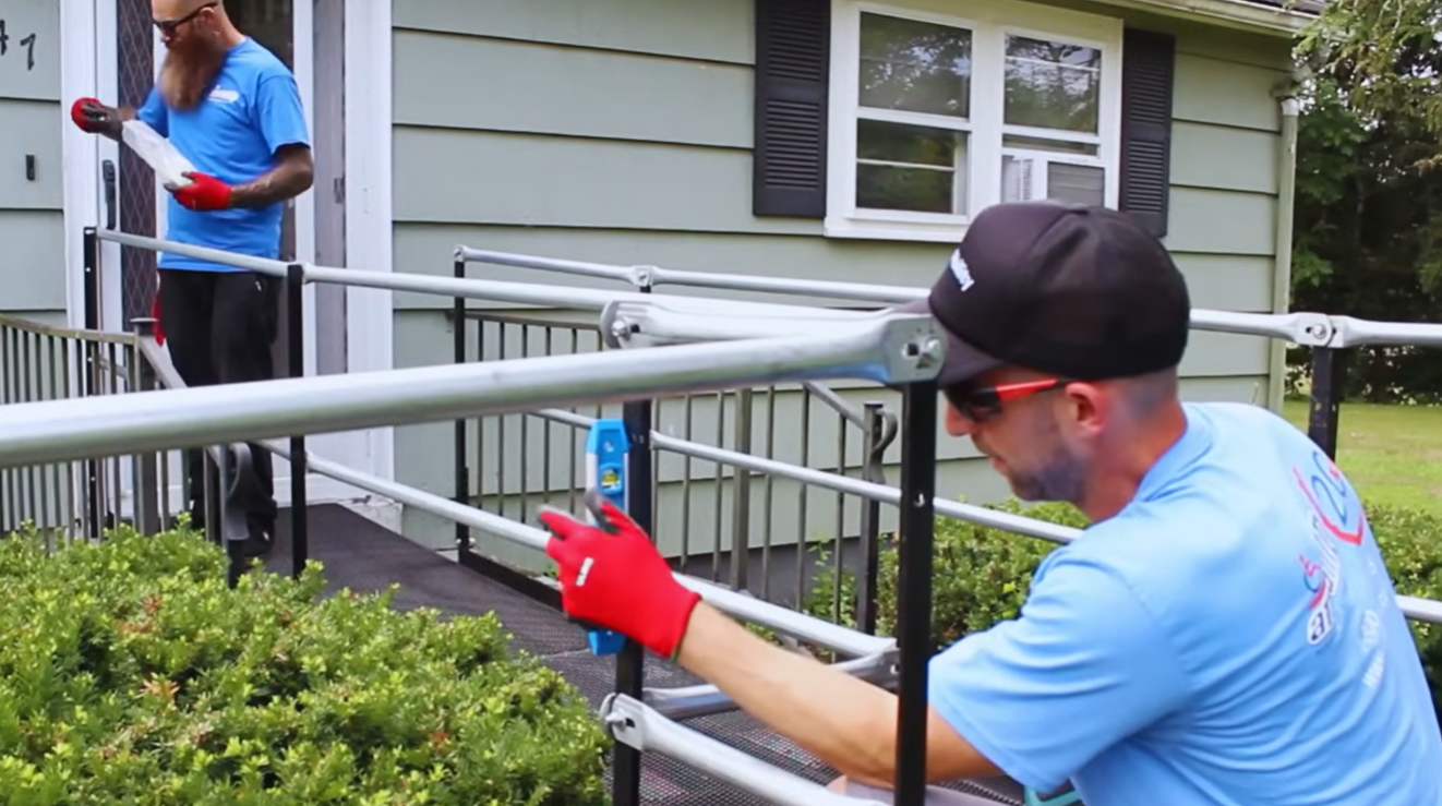 Two Amramp employees install a wheelchair ramp to provide access at a home