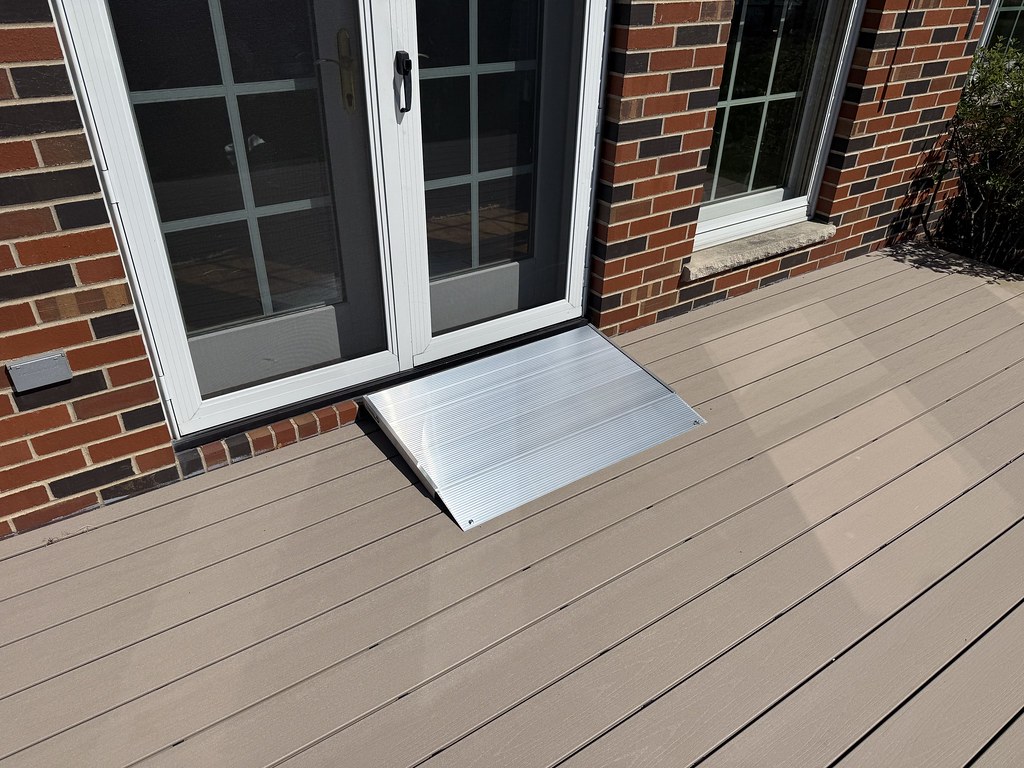 Portable aluminum threshold ramp installed at a sliding glass patio door for wheelchair accessibility.