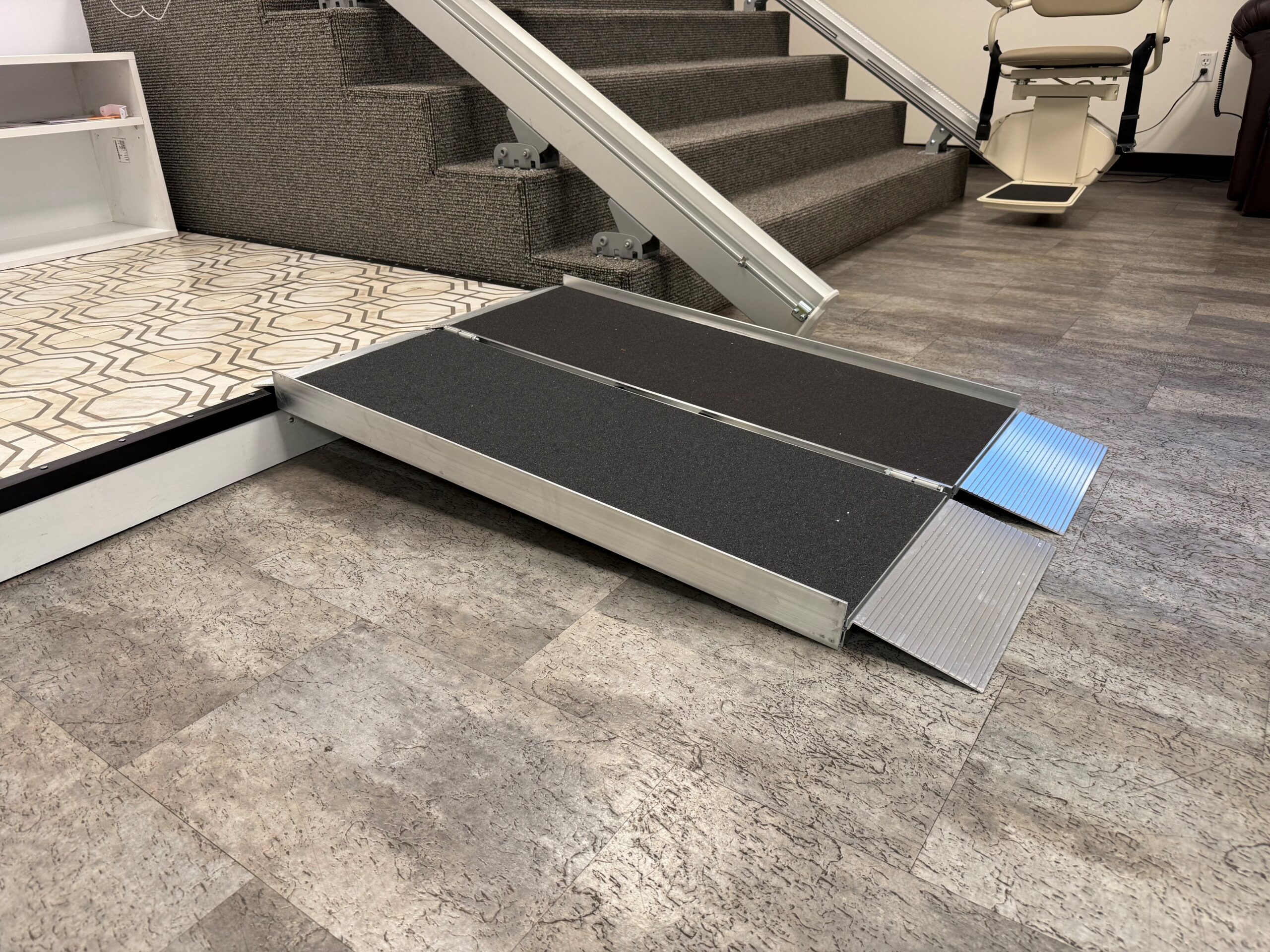 Portable aluminum wheelchair ramp displayed in an accessibility showroom for overcoming thresholds and small steps.
