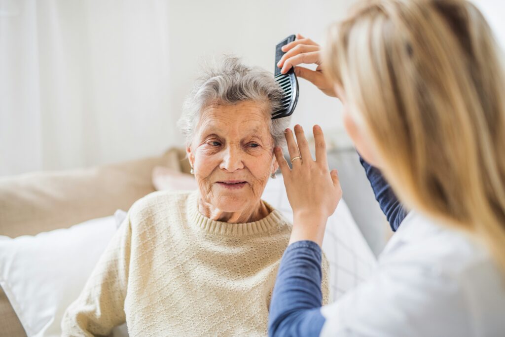 Caregiver assisting an older adult with personal grooming and daily care needs.