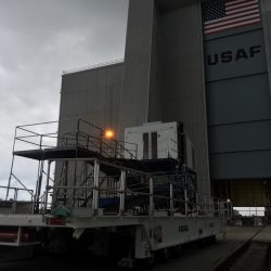 Elevated steel ramp and platform system with railings beside industrial equipment outside a hangar marked USAF.