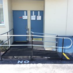L-shaped steel wheelchair ramp with handrails and a landing leading to a blue door at Westchester Animal Hospital.