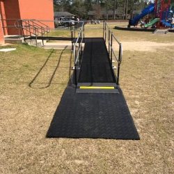 Portable wheelchair ramp providing accessible entry to a school building near a playground.