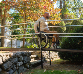 A man in a wheelchair moving forward along a raised bridge