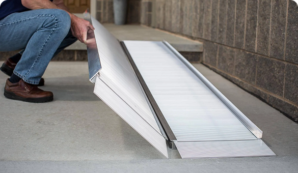 a person kneeling in front of a portable ramp as it is installed
