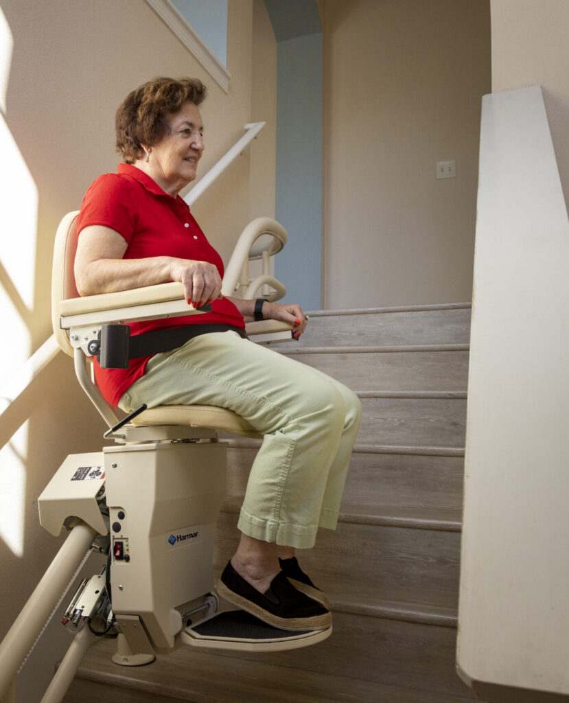 Older adult using a stair lift to safely travel up the stairs at a place of business.