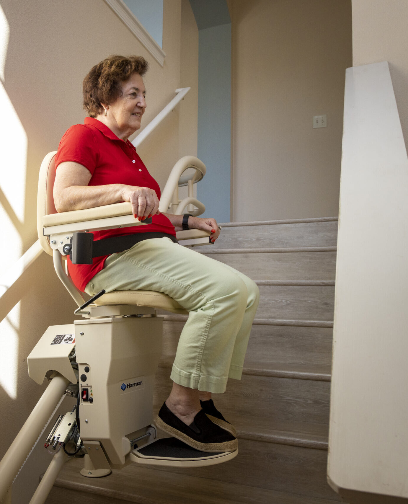 Older adult using a stair lift to safely travel up the stairs at a place of business.